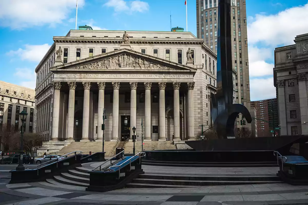 Classical-style building with columns and sculptures on the main facade, surrounded by a plaza with stairs and a modern sculpture in the foreground Classical-style building with columns and sculptures on the main facade, surrounded by a plaza with stairs and a modern sculpture in the foreground