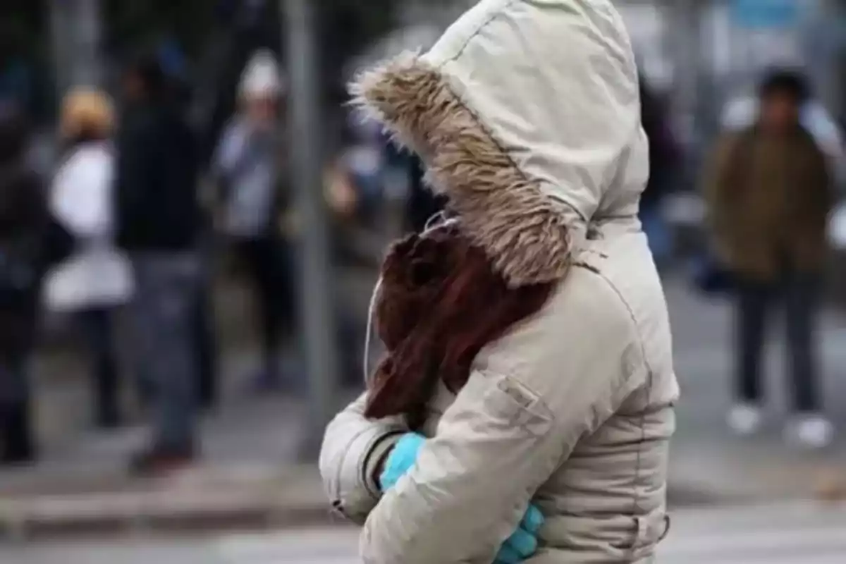 Persona abrigada con chamarra y guantes en la calle durante un día frío