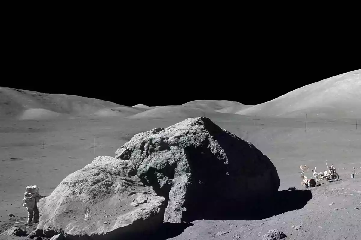 An astronaut explores a large rock on the lunar surface with a lunar vehicle parked nearby under a completely black sky. An astronaut explores a large rock on the lunar surface with a lunar vehicle parked nearby under a completely black sky.