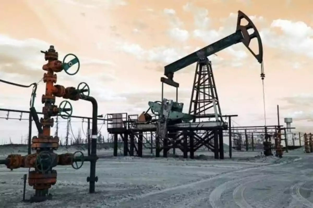 Campo petrolero con maquinaria de extracción y válvulas bajo un cielo nublado al atardecer Campo petrolero con maquinaria de extracción y válvulas bajo un cielo nublado al atardecer