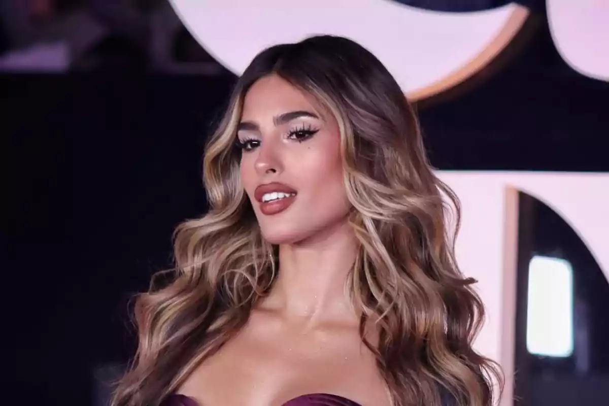 Mujer joven con cabello largo y ondulado, maquillaje elegante y vestido escotado en un evento nocturno