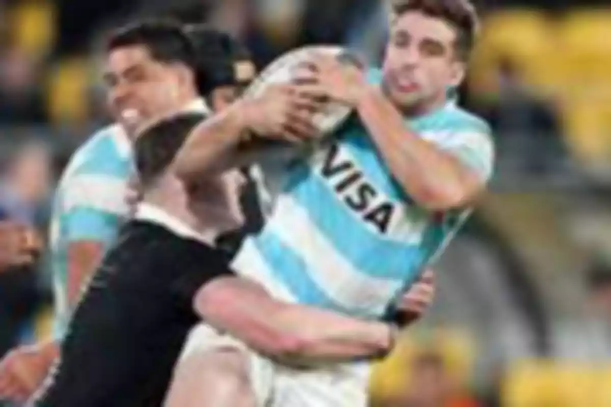 Rugby player in a light blue and white jersey holds the ball while being tackled by an opponent dressed in black during a match. Rugby player in a light blue and white jersey holds the ball while being tackled by an opponent dressed in black during a match.