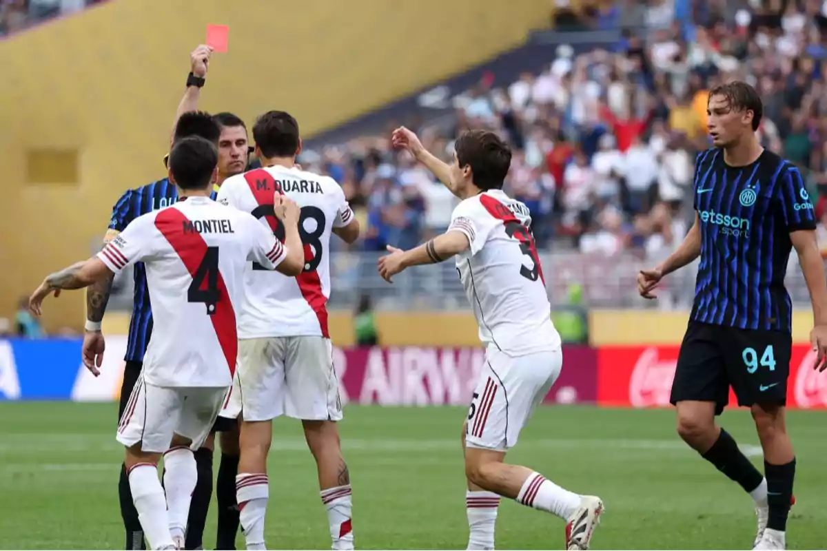 Un árbitro muestra una tarjeta roja durante un partido de fútbol mientras varios jugadores de ambos equipos reaccionan en el campo Un árbitro muestra una tarjeta roja durante un partido de fútbol mientras varios jugadores de ambos equipos reaccionan en el campo