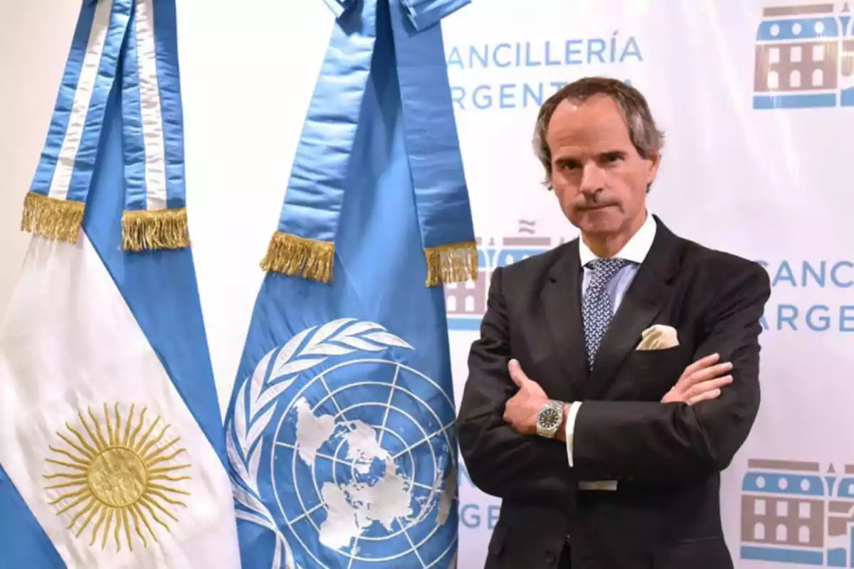 Man in a suit with his arms crossed posing next to the flags of Argentina and the UN at an official event Man in a suit with his arms crossed posing next to the flags of Argentina and the UN at an official event