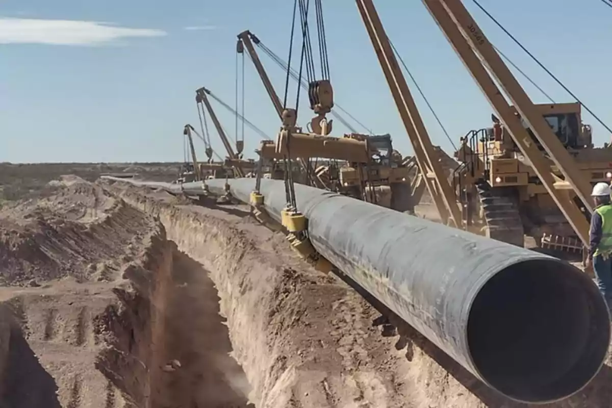 Heavy machinery installing a gas pipeline in a trench in a desert area