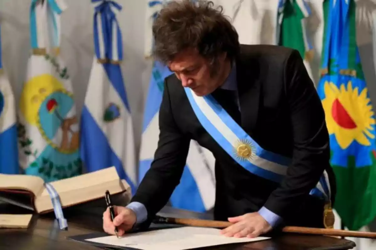 Man wearing the Argentine presidential sash signing an official document at a solemn ceremony
