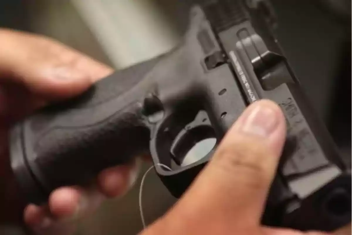 Person holding a black gun with both hands Person holding a black gun with both hands