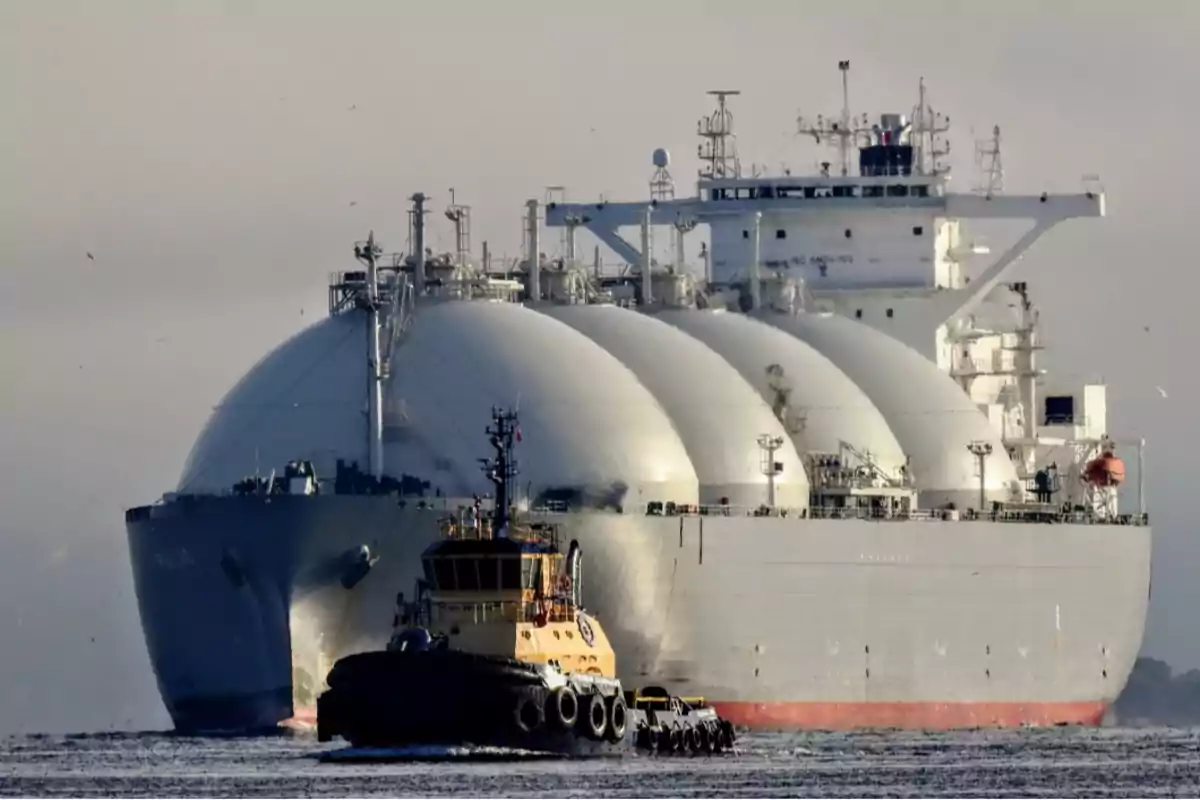 A large LNG carrier transporting liquefied natural gas is escorted by a tugboat at sea. A large LNG carrier transporting liquefied natural gas is escorted by a tugboat at sea.