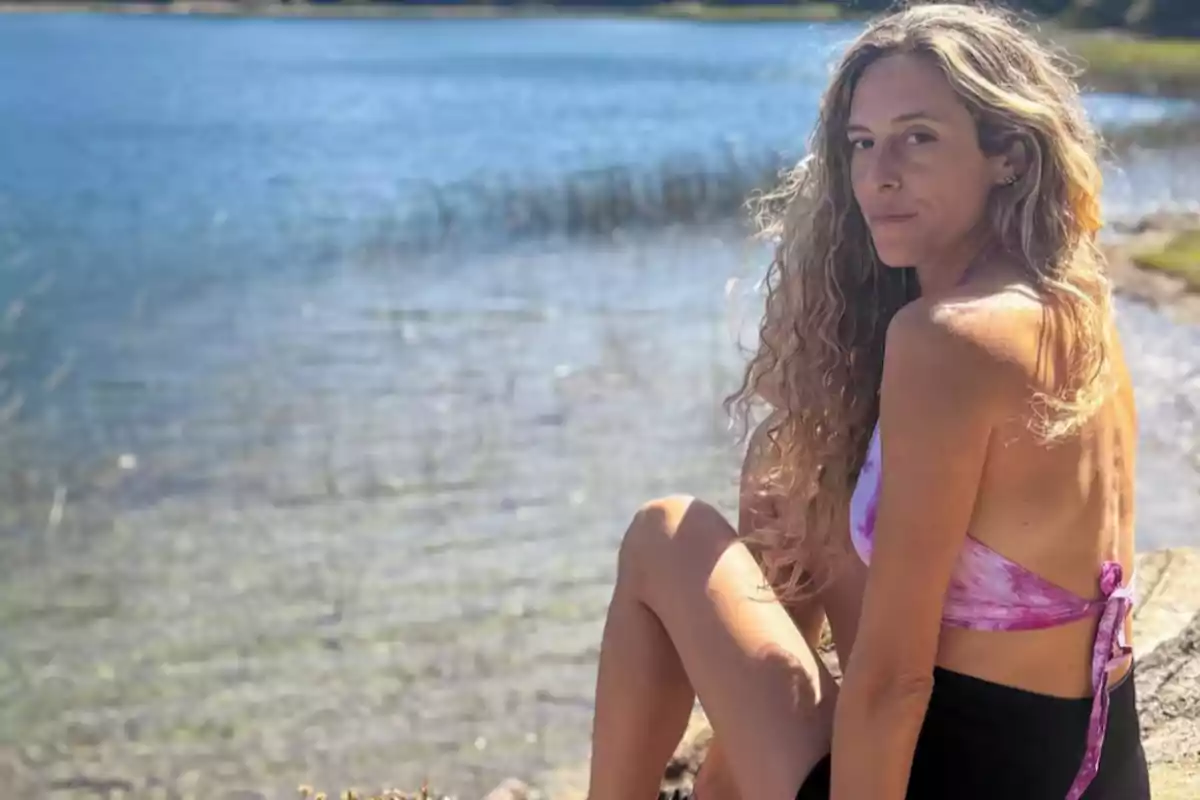 Woman with long, curly hair sitting by a lake on a sunny day Woman with long, curly hair sitting by a lake on a sunny day