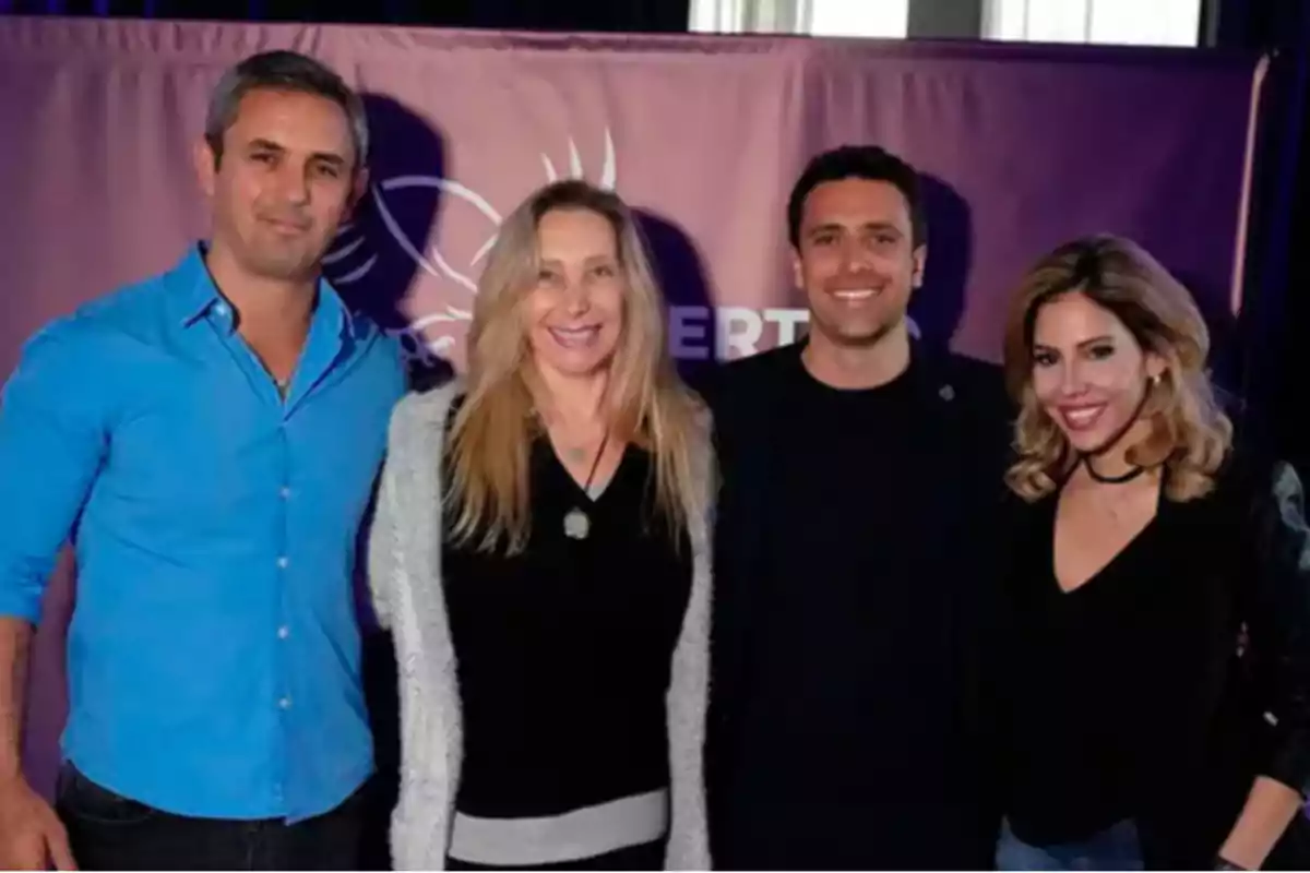 Cuatro personas posan sonrientes frente a un fondo morado Cuatro personas posan sonrientes frente a un fondo morado