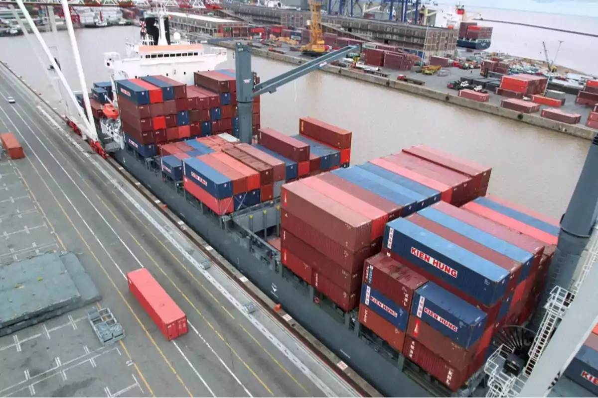 Barco de carga en un puerto con numerosos contenedores apilados y grúas alrededor