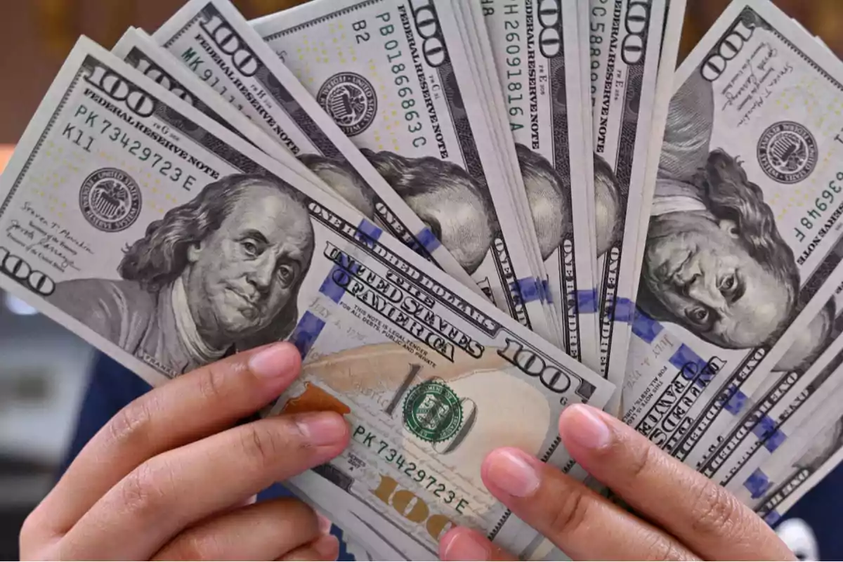 Hands holding several one-hundred-dollar bills fanned out Hands holding several one-hundred-dollar bills fanned out