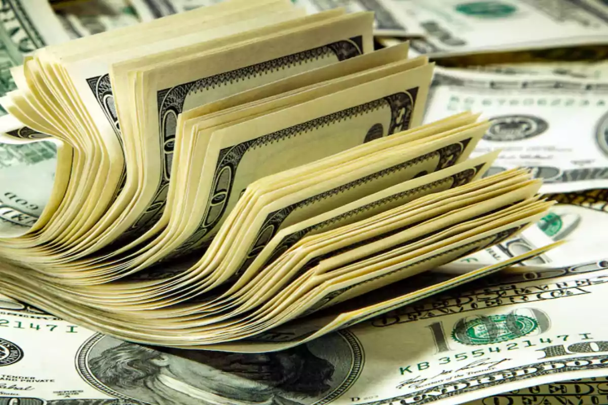 Stacks of U.S. dollar bills piled up and spread out over a surface covered with more bills Stacks of U.S. dollar bills piled up and spread out over a surface covered with more bills