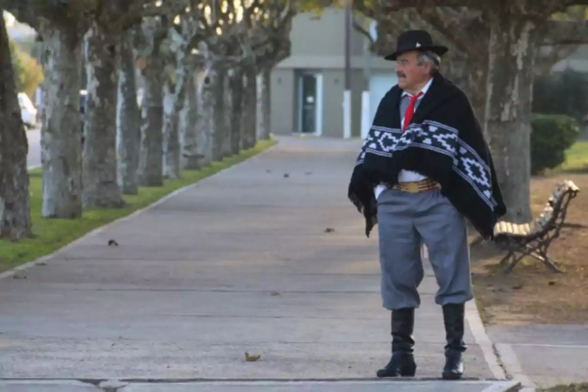 Man dressed in traditional gaucho clothing standing on a tree-lined sidewalk Man dressed in traditional gaucho clothing standing on a tree-lined sidewalk