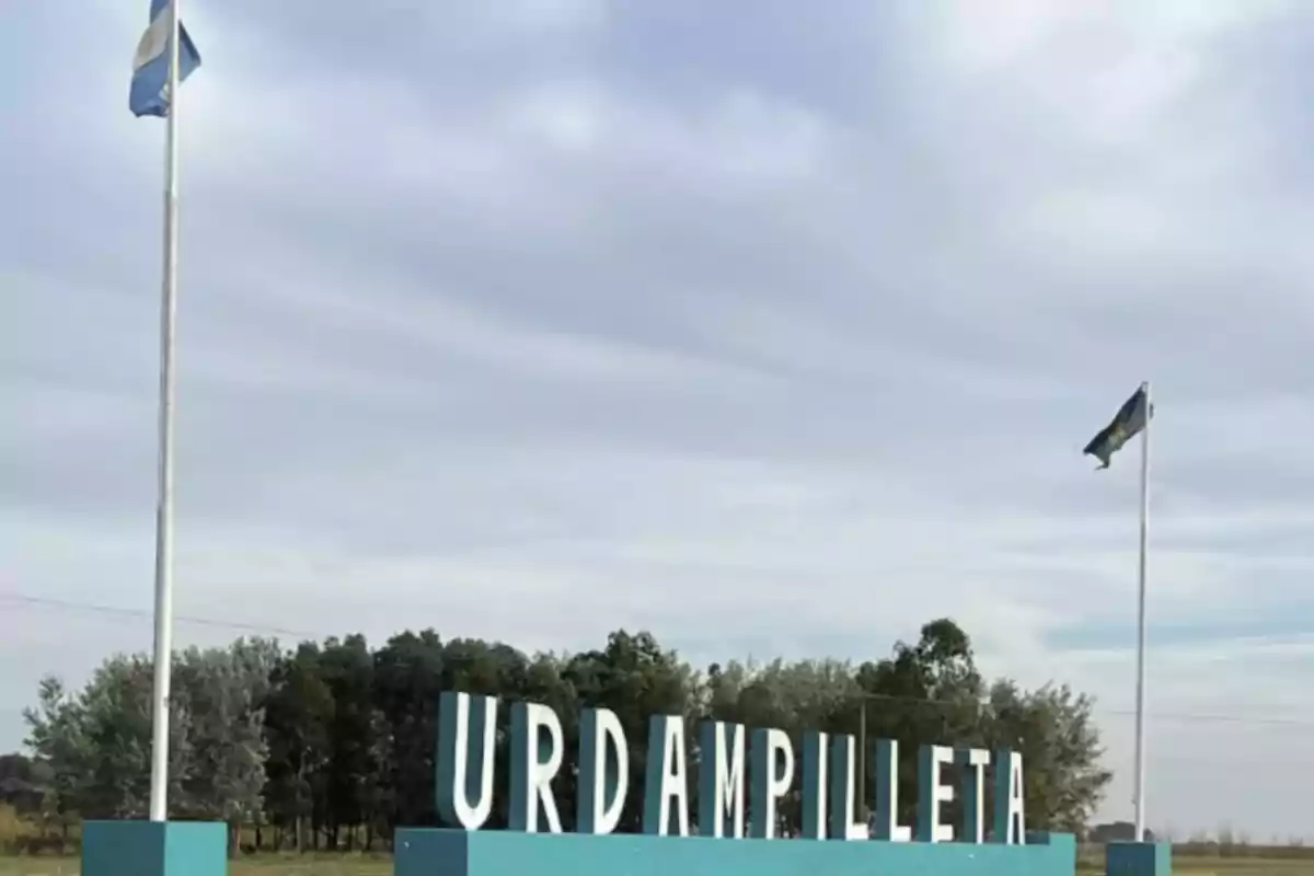 Welcome sign to Urdampilleta with two Argentine flags and trees in the background Welcome sign to Urdampilleta with two Argentine flags and trees in the background