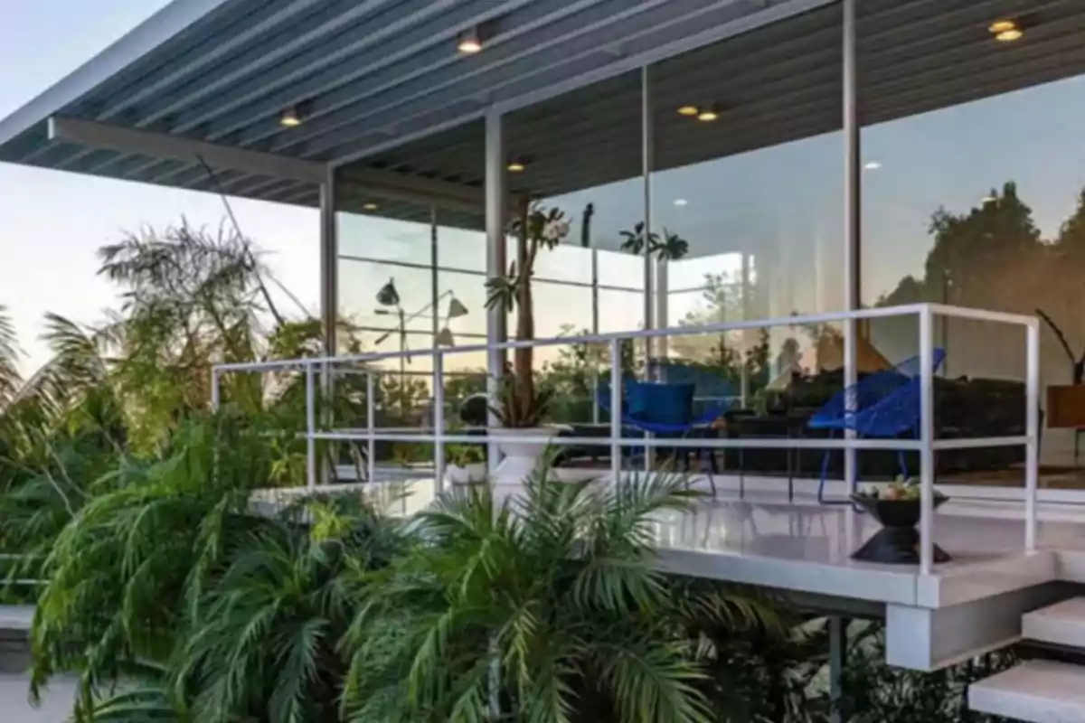 Modern terrace with blue chairs and plants, surrounded by large windows and greenery Modern terrace with blue chairs and plants, surrounded by large windows and greenery