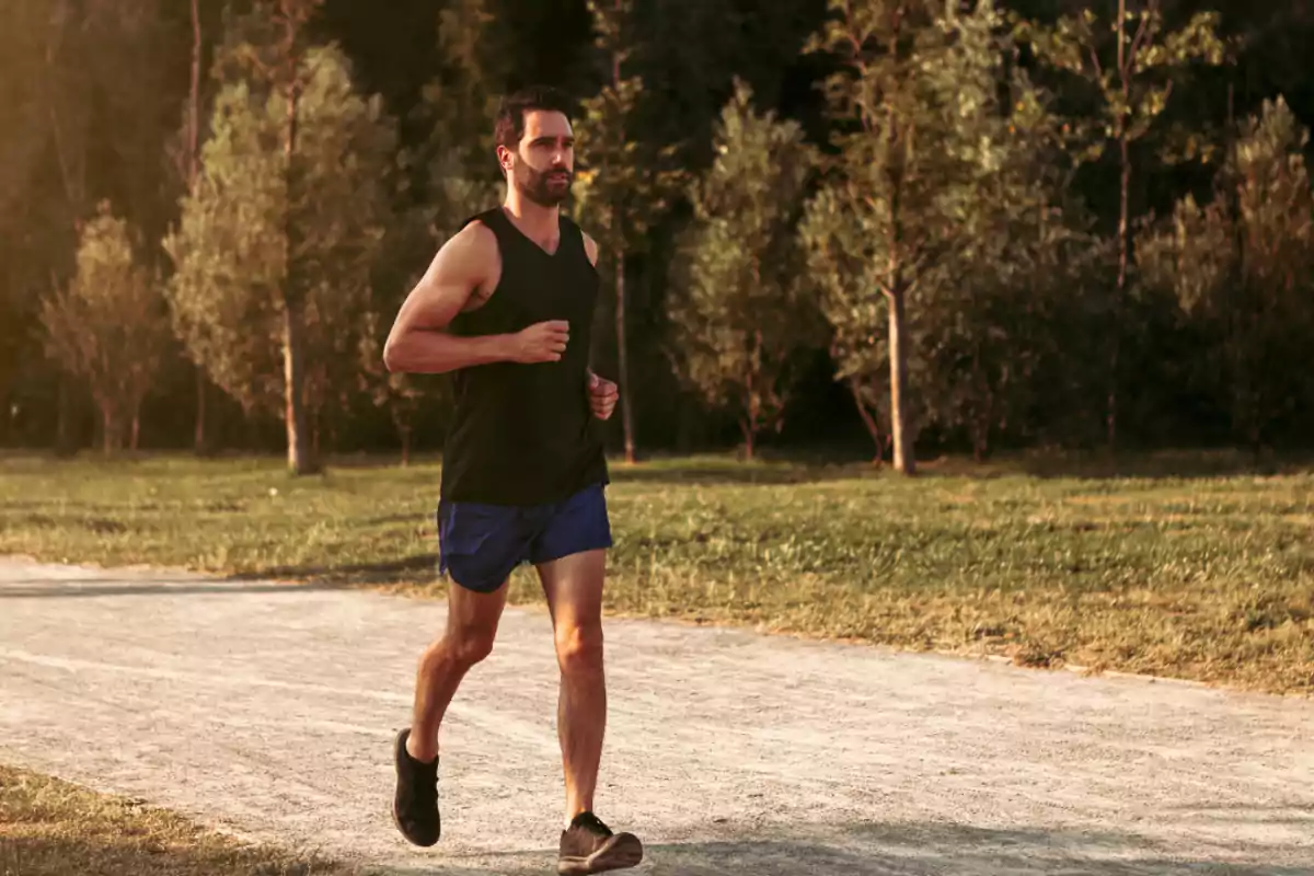 Hombre corriendo por un sendero en un parque rodeado de árboles al atardecer Hombre corriendo por un sendero en un parque rodeado de árboles al atardecer