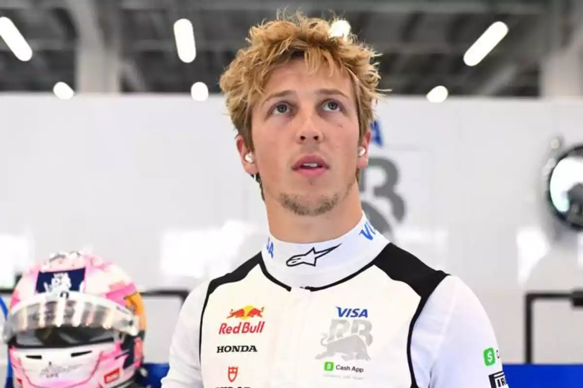 Motorsport driver wearing his team's black and white uniform inside a racing garage, with a racing helmet in the background Motorsport driver wearing his team's black and white uniform inside a racing garage, with a racing helmet in the background