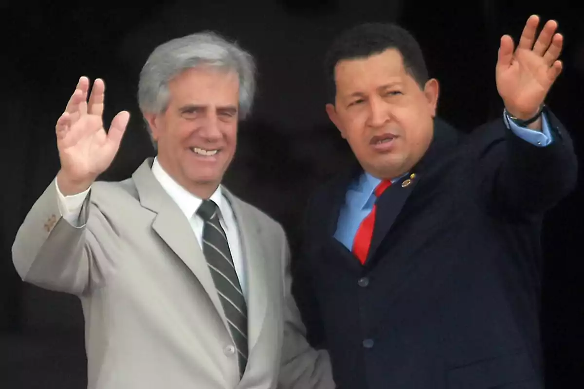 Two men in suits wave and smile with their hands raised. Two men in suits wave and smile with their hands raised.