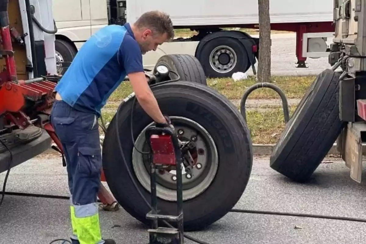 Hombre reparando una llanta de camión en la calle usando herramientas especializadas Hombre reparando una llanta de camión en la calle usando herramientas especializadas