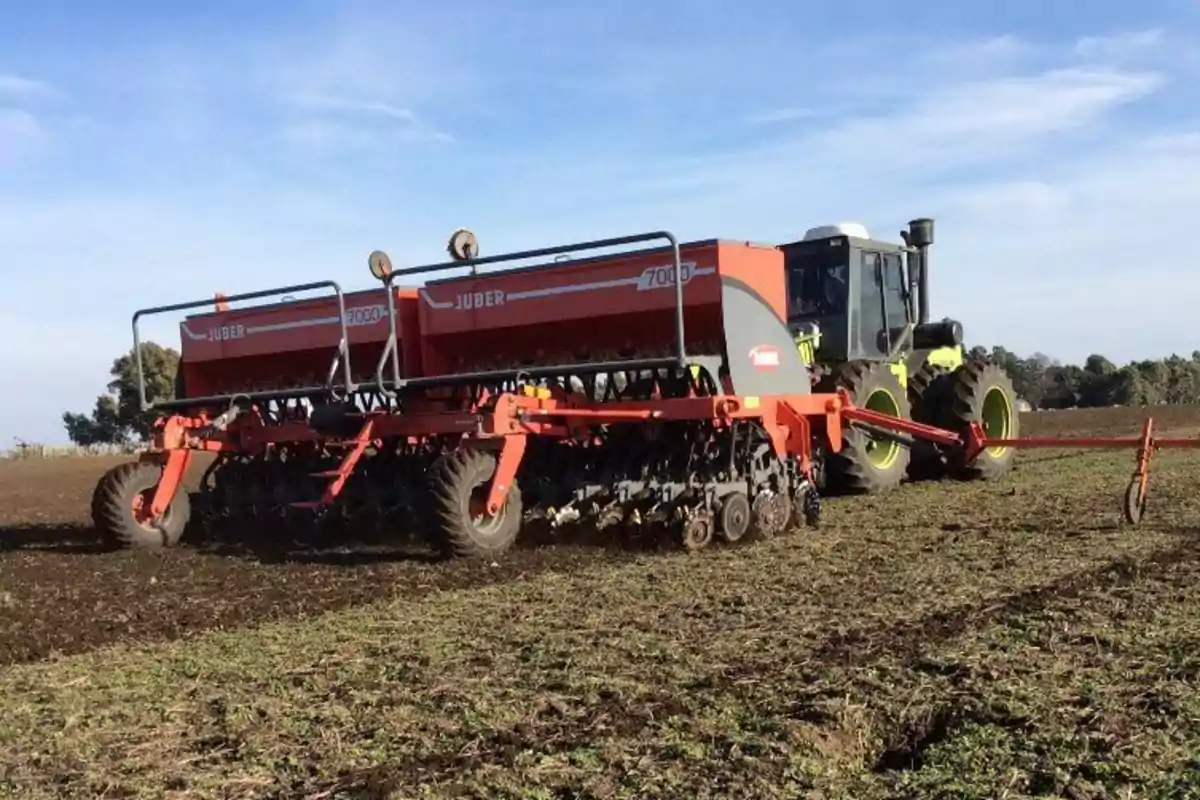 Tractor agrícola trabajando en un campo con una sembradora de gran tamaño en un día soleado