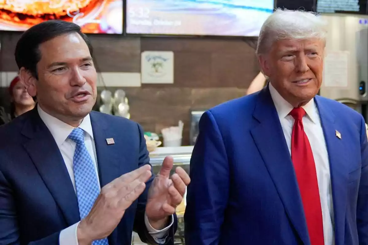 Two men in blue suits are talking and smiling inside a restaurant or café. Two men in blue suits are talking and smiling inside a restaurant or café.