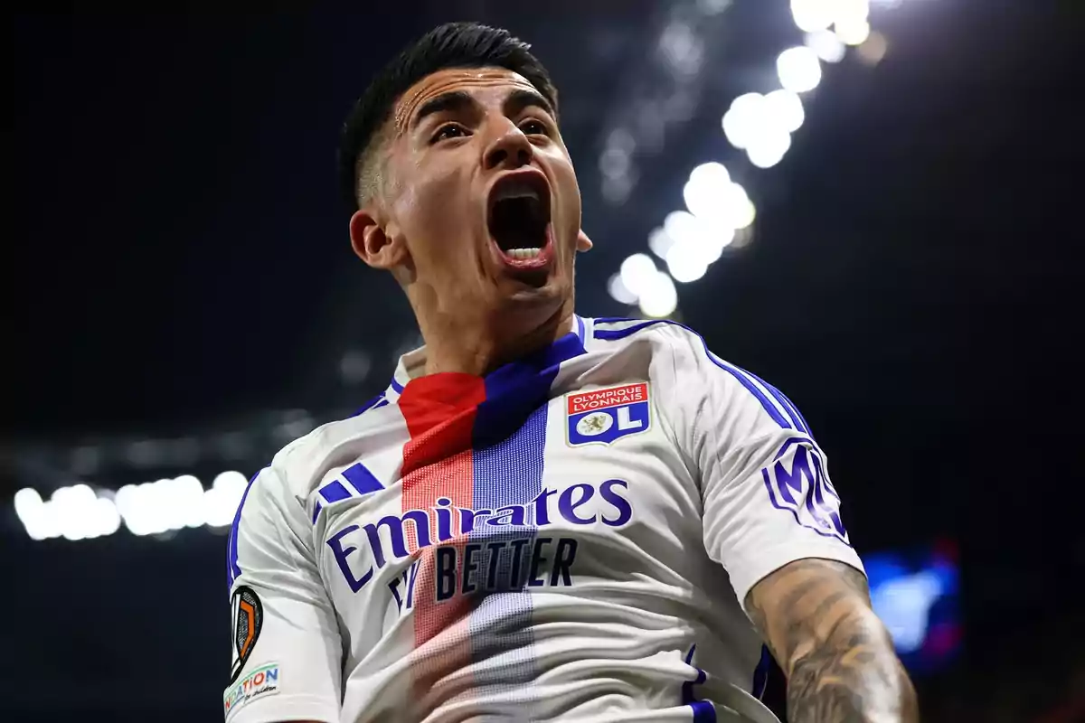 Futbolista del Olympique de Lyon celebrando un gol con una expresión de euforia en el rostro durante un partido nocturno Futbolista del Olympique de Lyon celebrando un gol con una expresión de euforia en el rostro durante un partido nocturno