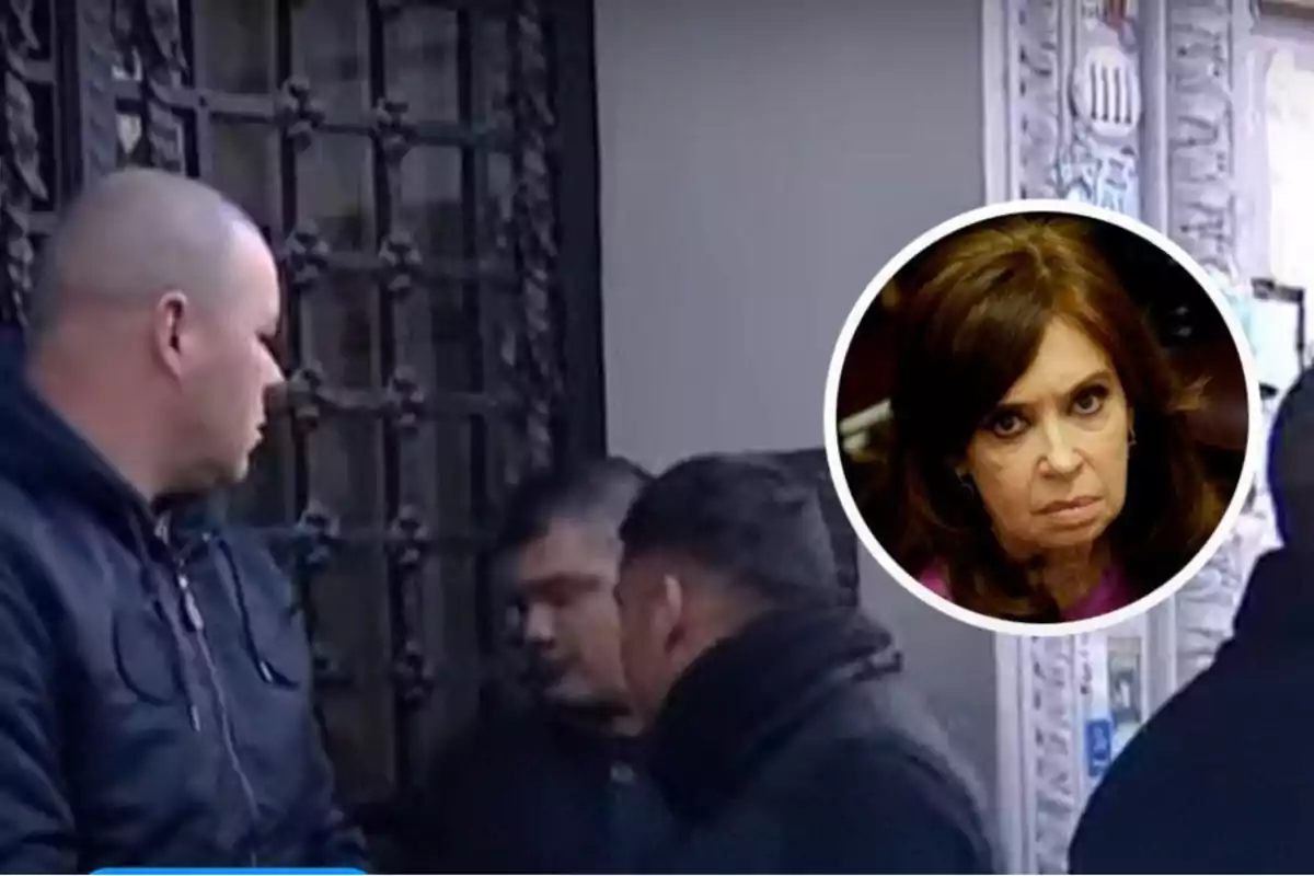 Varios hombres con ropa oscura están reunidos frente a una puerta de hierro y en la esquina superior derecha aparece el rostro de una mujer de cabello castaño con expresión seria dentro de un círculo blanco.
