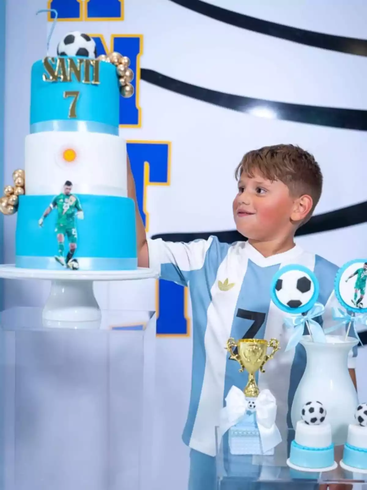 Boy wearing a light blue and white soccer jersey celebrating his birthday with a soccer-themed cake and trophies. Boy wearing a light blue and white soccer jersey celebrating his birthday with a soccer-themed cake and trophies.