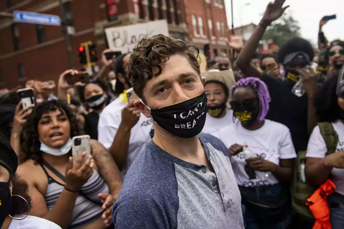 Hombre con mascarilla que dice I can't breathe rodeado de manifestantes en una protesta