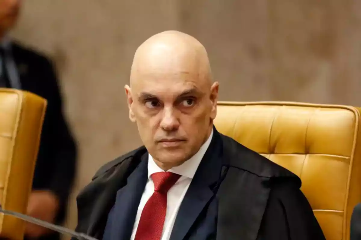 Hombre calvo con traje y corbata roja sentado en una silla de cuero amarilla mirando hacia un lado en un entorno formal Hombre calvo con traje y corbata roja sentado en una silla de cuero amarilla mirando hacia un lado en un entorno formal