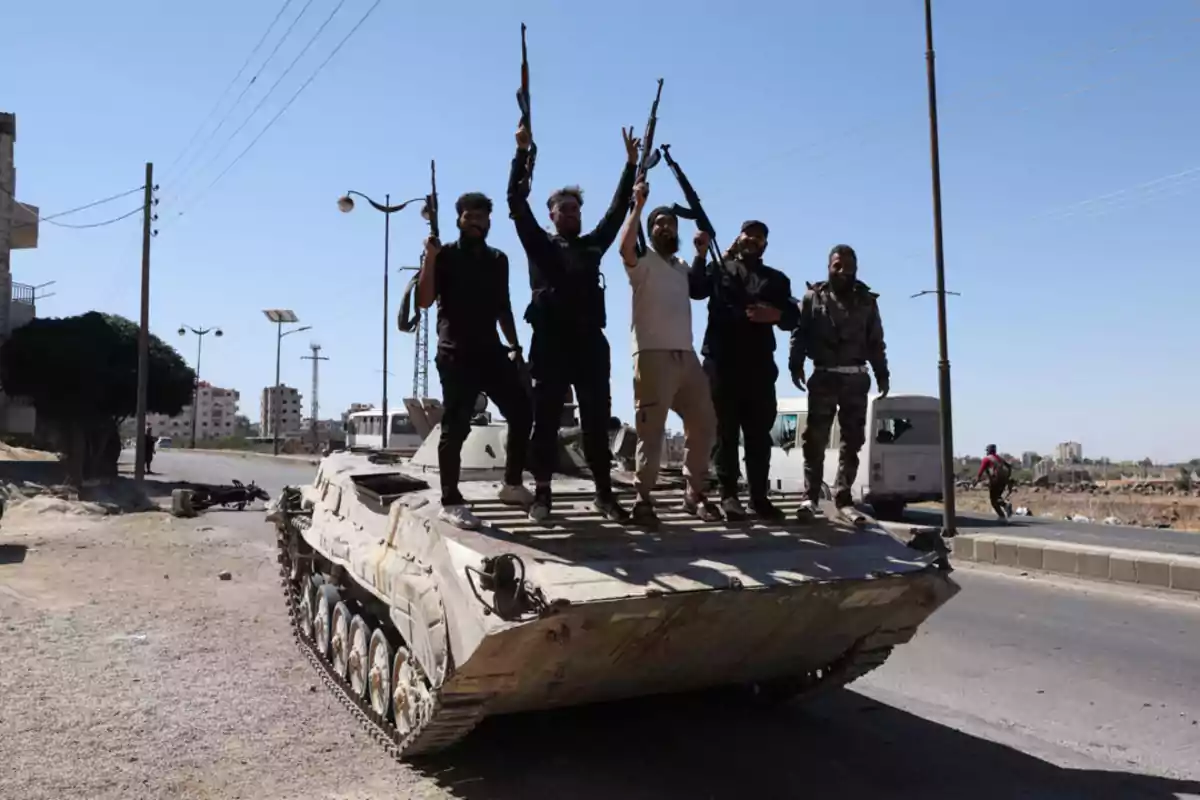 Five armed men pose on an armored vehicle on an urban street under a clear sky. Five armed men pose on an armored vehicle on an urban street under a clear sky.