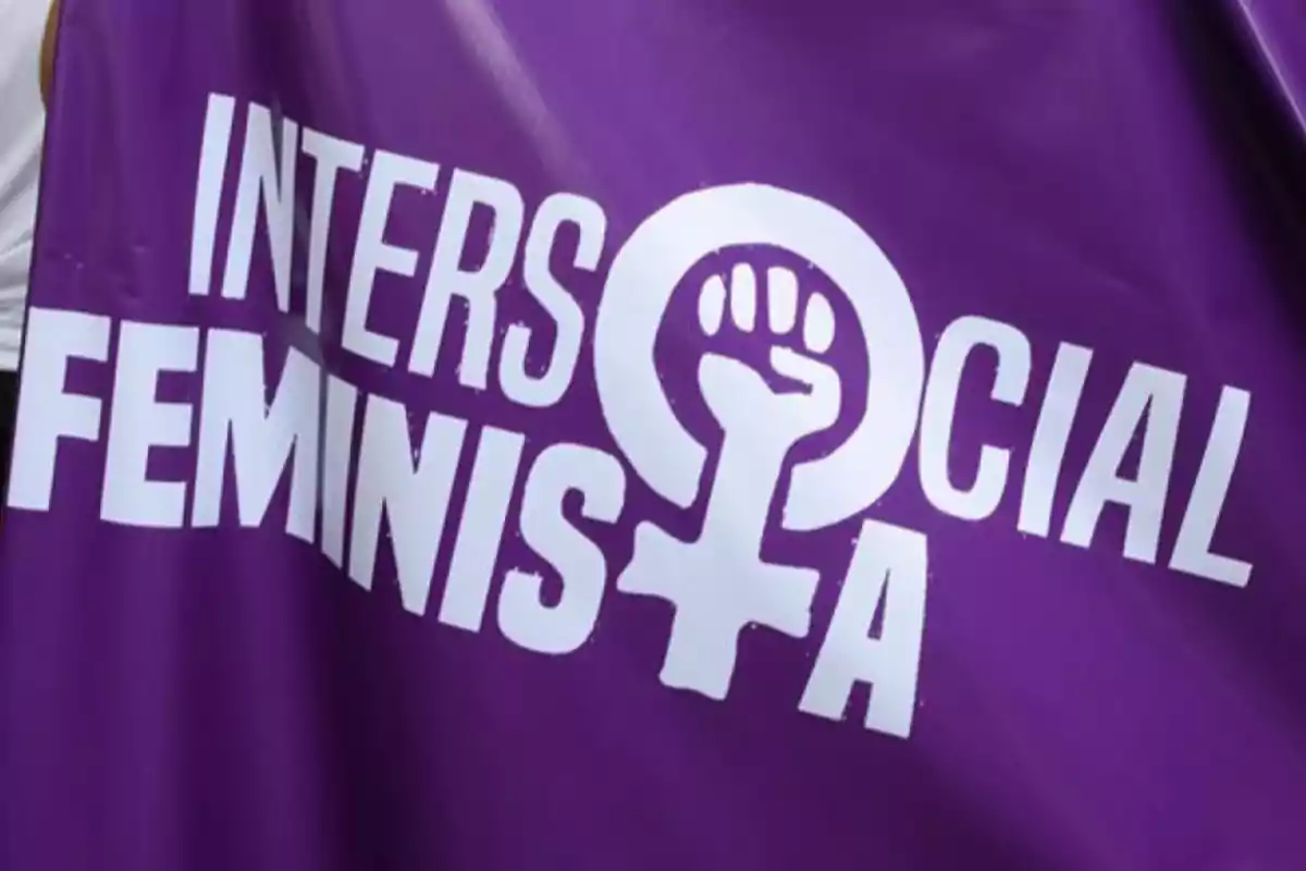 Pancarta morada con las palabras Intersocial Feminista en letras blancas y el símbolo feminista con un puño en el centro.