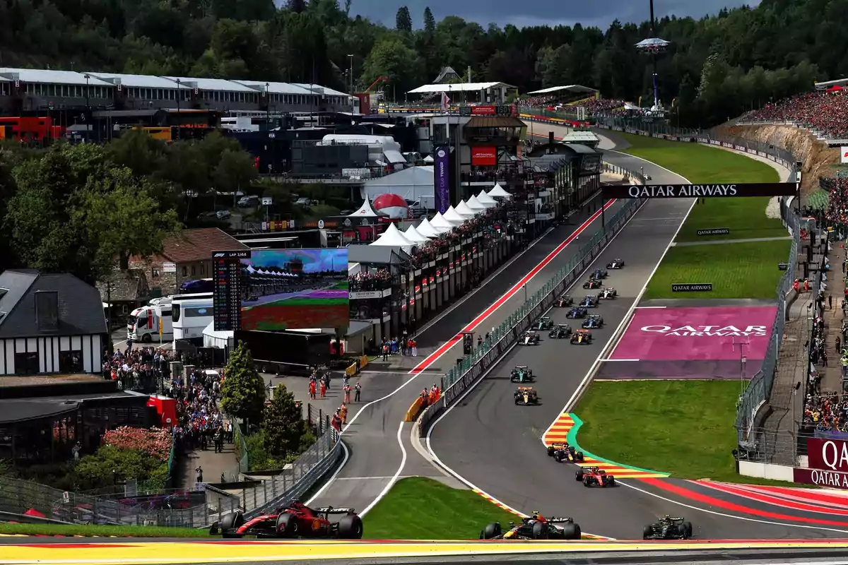 Panoramic view of a Formula 1 race at the Spa-Francorchamps circuit with several cars on track and grandstands full of spectators Panoramic view of a Formula 1 race at the Spa-Francorchamps circuit with several cars on track and grandstands full of spectators