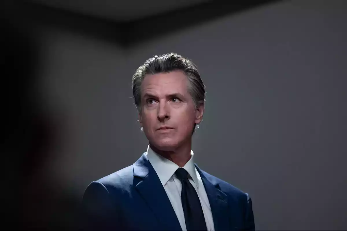 Gray-haired man in a blue suit and dark tie looking to the side in a room with a gray background Gray-haired man in a blue suit and dark tie looking to the side in a room with a gray background