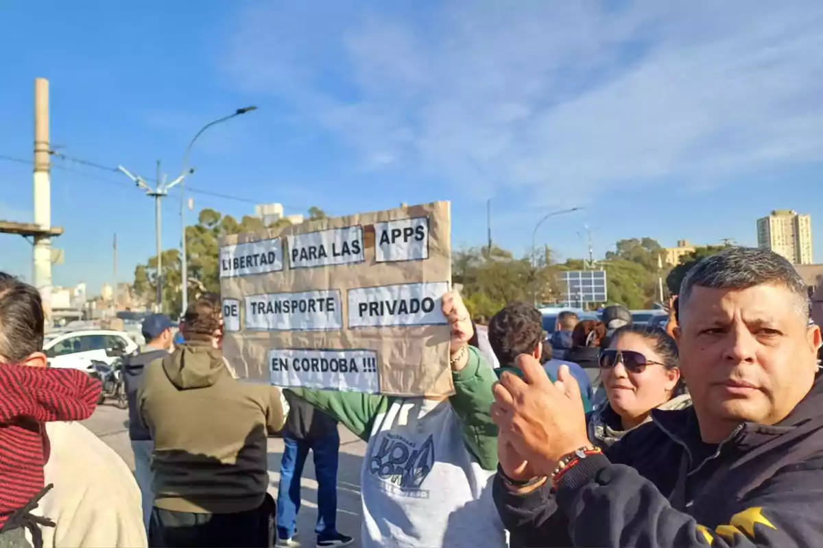 People protesting in the street while one of them holds a sign demanding freedom for private transportation apps in Córdoba.