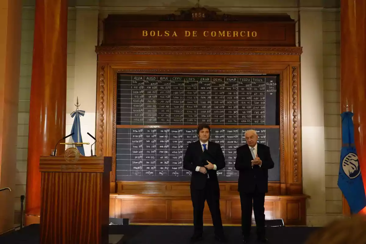 Dos hombres de traje de pie frente a un pizarrón de cotizaciones en el interior de la Bolsa de Comercio de Buenos Aires Dos hombres de traje de pie frente a un pizarrón de cotizaciones en el interior de la Bolsa de Comercio de Buenos Aires