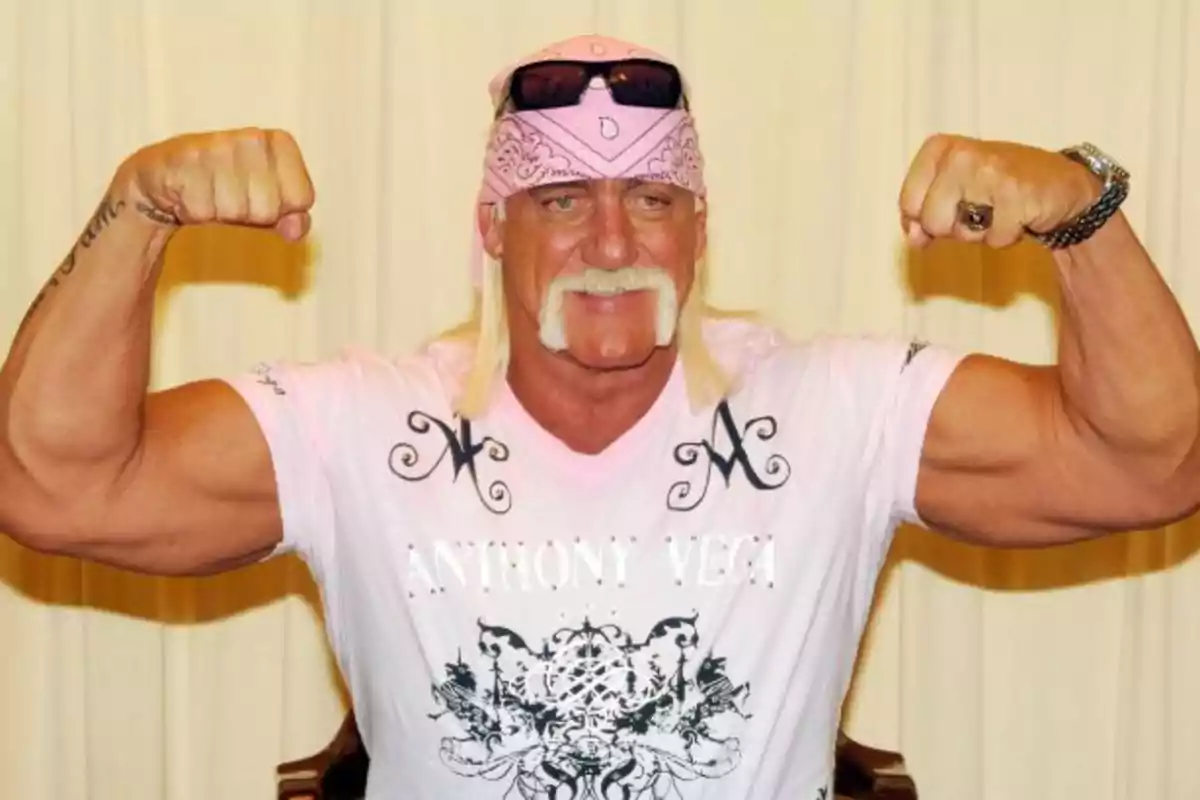 Muscular man with a mustache and long blond hair wearing a pink bandana and a light-colored t-jersey while showing off his biceps Muscular man with a mustache and long blond hair wearing a pink bandana and a light-colored t-jersey while showing off his biceps
