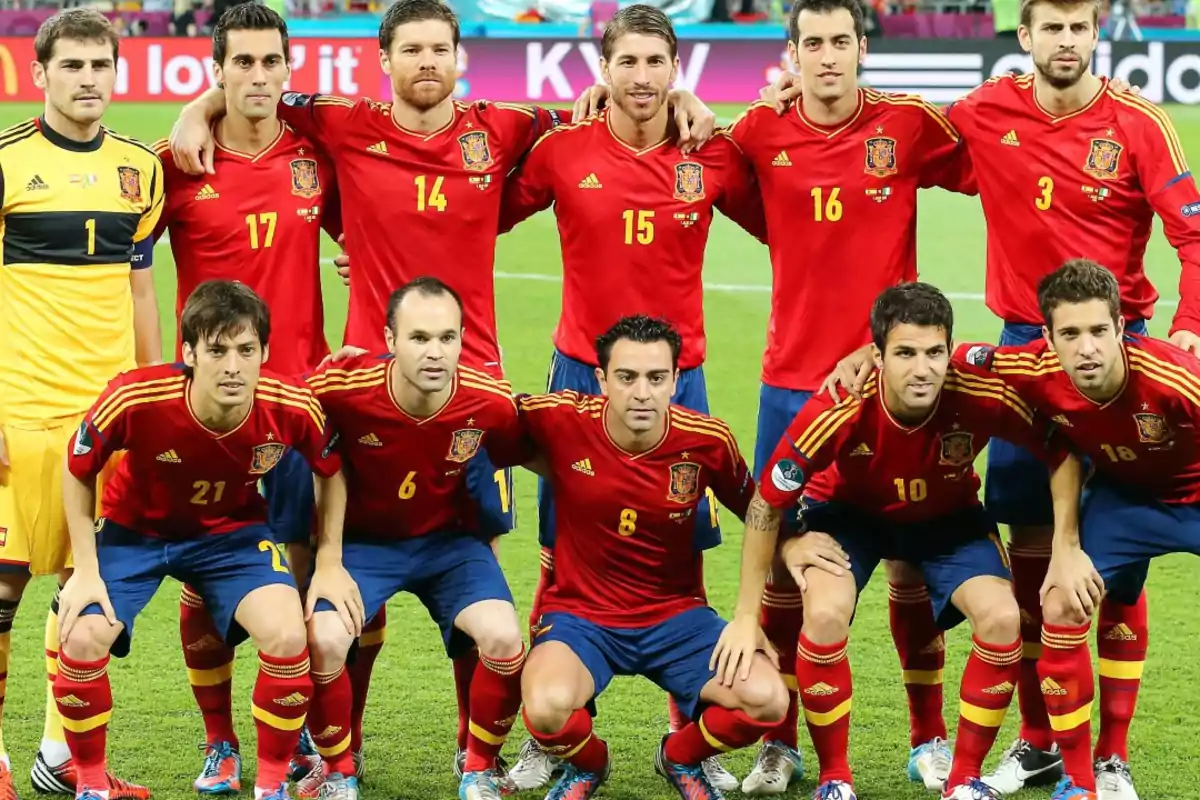 Once jugadores de la selección española de fútbol posan juntos en el campo antes de un partido, todos llevan el uniforme rojo con detalles amarillos y pantalones azules Once jugadores de la selección española de fútbol posan juntos en el campo antes de un partido, todos llevan el uniforme rojo con detalles amarillos y pantalones azules