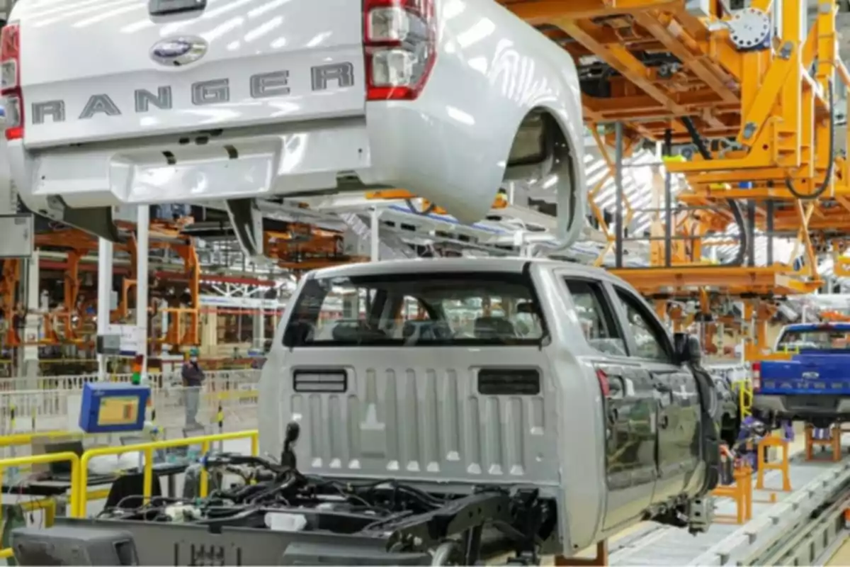 Línea de ensamblaje de camionetas en una fábrica automotriz con varias carrocerías y estructuras en proceso de montaje Línea de ensamblaje de camionetas en una fábrica automotriz con varias carrocerías y estructuras en proceso de montaje