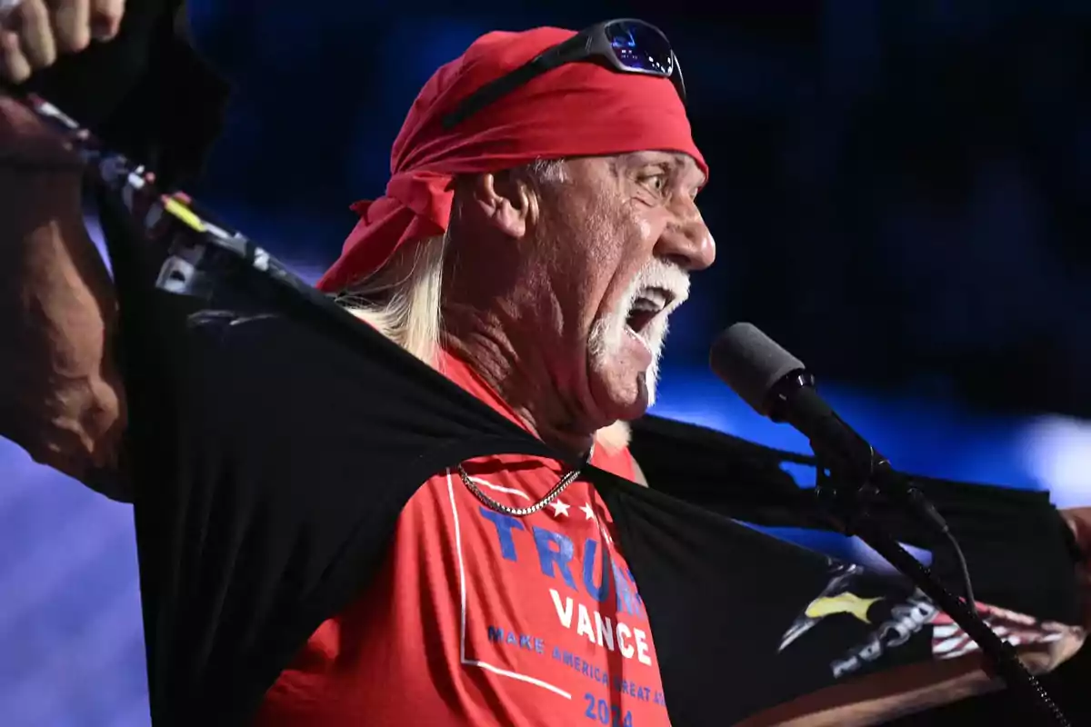 Man with a red bandana and sunglasses on his head tearing his black t-jersey in front of a microphone while screaming Man with a red bandana and sunglasses on his head tearing his black t-jersey in front of a microphone while screaming