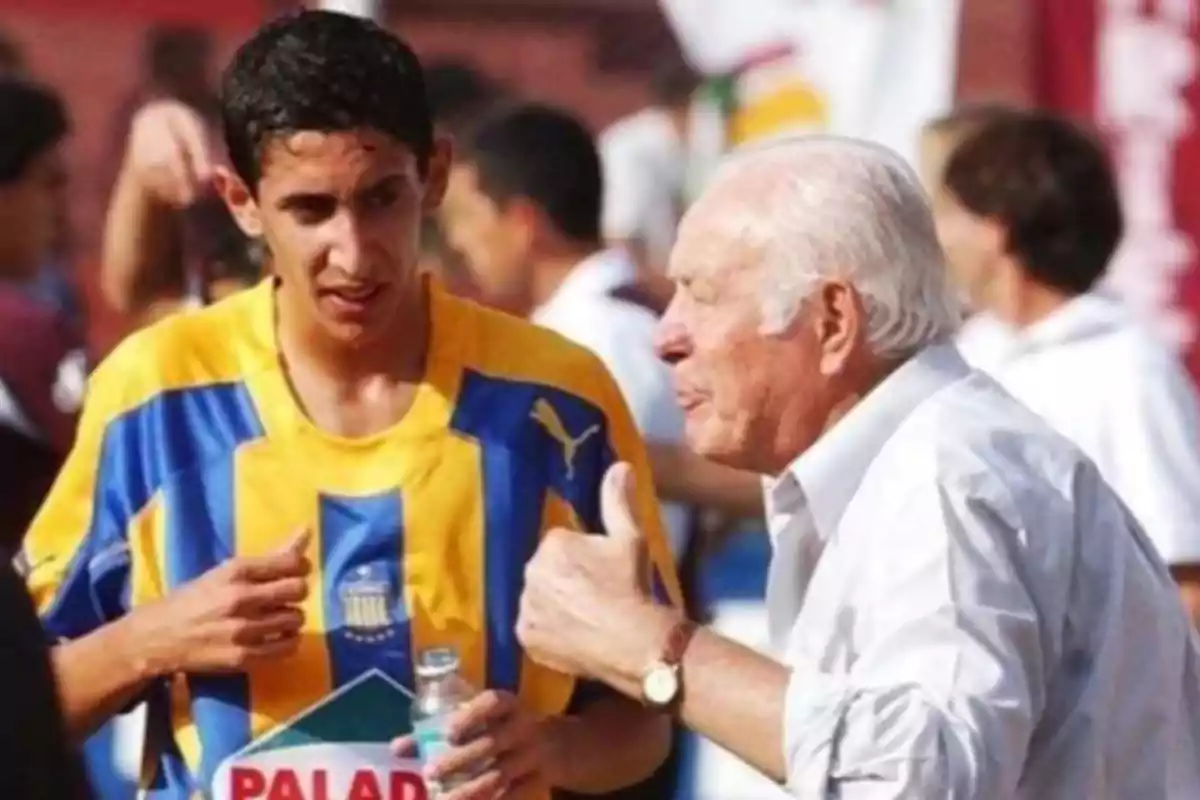 Un joven futbolista con camiseta amarilla y azul conversa con un hombre mayor de cabello canoso que le muestra el pulgar hacia arriba en señal de aprobación Un joven futbolista con camiseta amarilla y azul conversa con un hombre mayor de cabello canoso que le muestra el pulgar hacia arriba en señal de aprobación