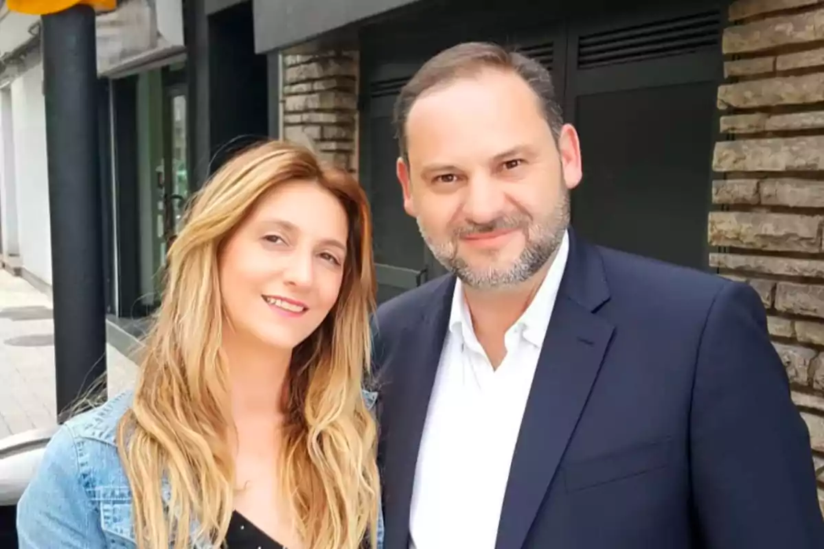 A woman and a man pose together and smile on an urban street.