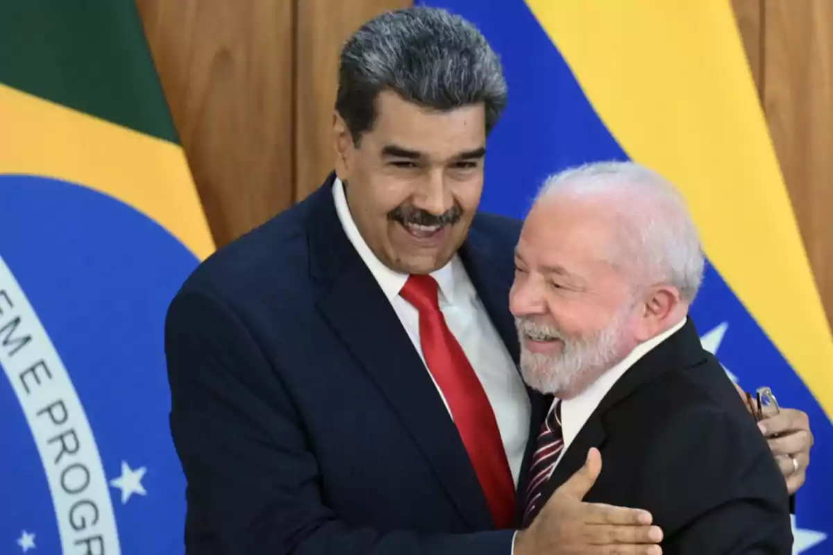 Dos hombres de traje se abrazan y sonríen frente a banderas de Brasil y Venezuela Dos hombres de traje se abrazan y sonríen frente a banderas de Brasil y Venezuela