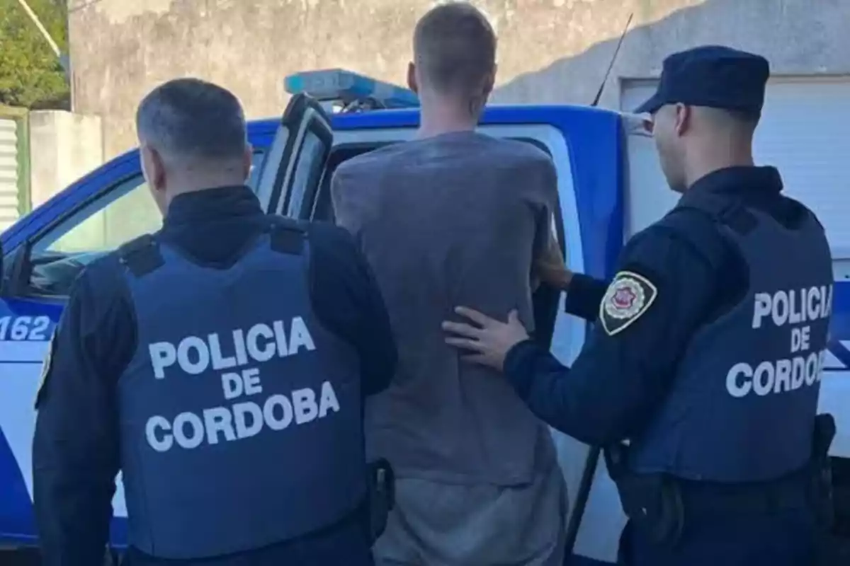 Dos policías de Córdoba escoltan a un hombre hacia una patrulla policial Dos policías de Córdoba escoltan a un hombre hacia una patrulla policial