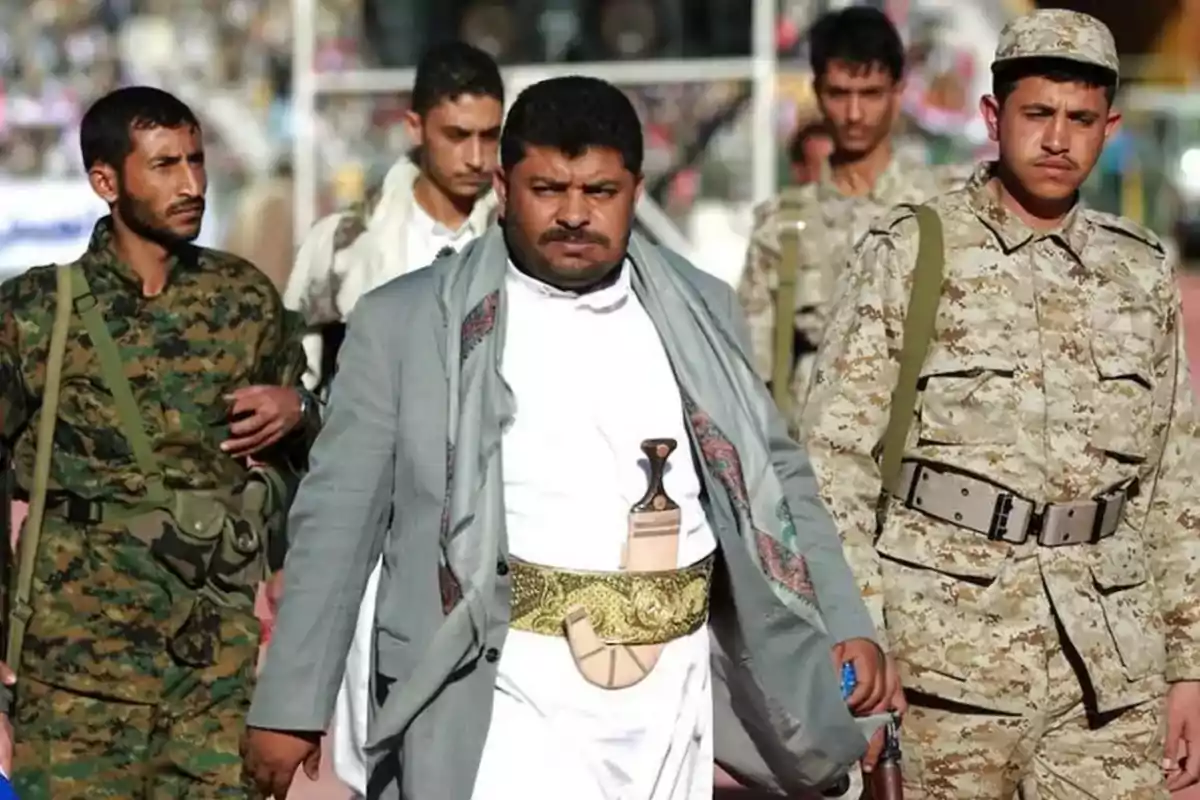 Un grupo de hombres con vestimenta militar y tradicional camina juntos en un entorno al aire libre Un grupo de hombres con vestimenta militar y tradicional camina juntos en un entorno al aire libre