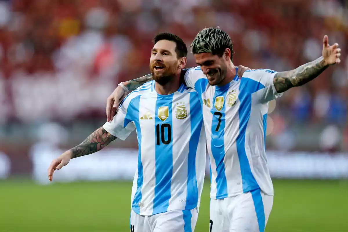 Two players from the Argentine national team celebrate hugging on the field during a match. Two players from the Argentine national team celebrate hugging on the field during a match.