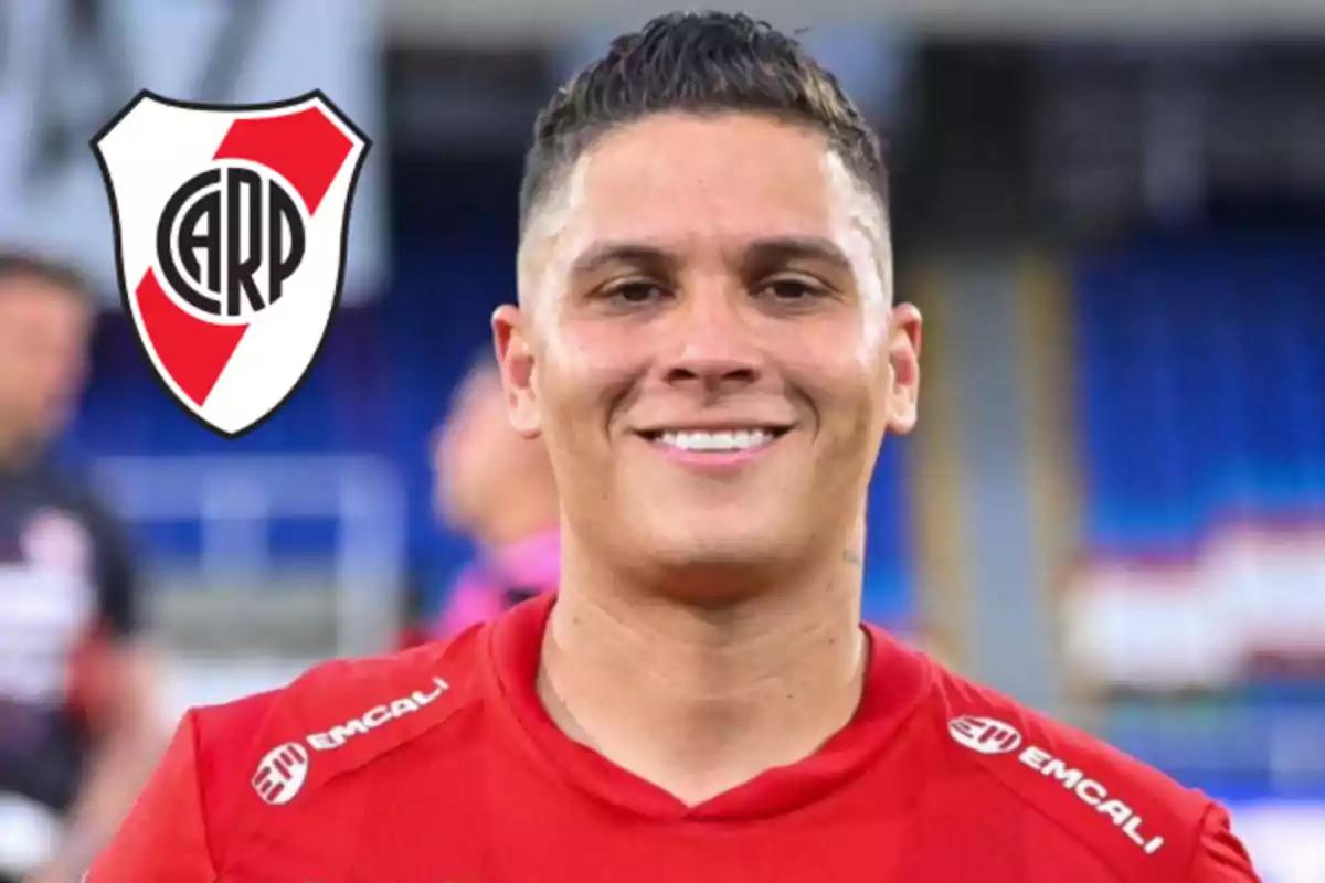 Smiling player wearing a red jersey with the River Plate crest in the background