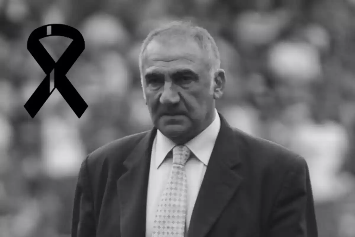 Man in a suit in a black and white image with a black mourning ribbon in the upper left corner