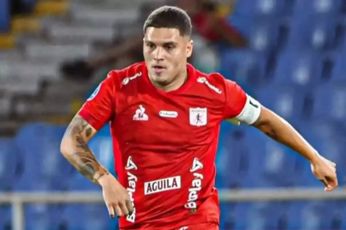 Soccer player in a red uniform in action during a match in a stadium with blue stands in the background Soccer player in a red uniform in action during a match in a stadium with blue stands in the background
